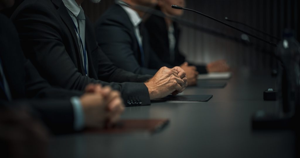 Diskretion, Männer im Anzug an einem Tisch sitzend