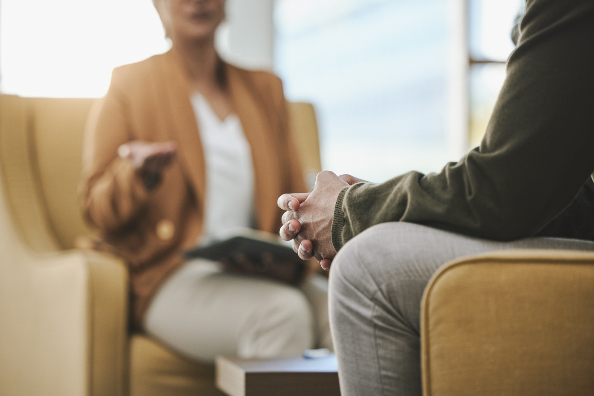 Zwei Personen im Gespräch in einem hellen Raum, eine Person spricht, die andere hört zu.